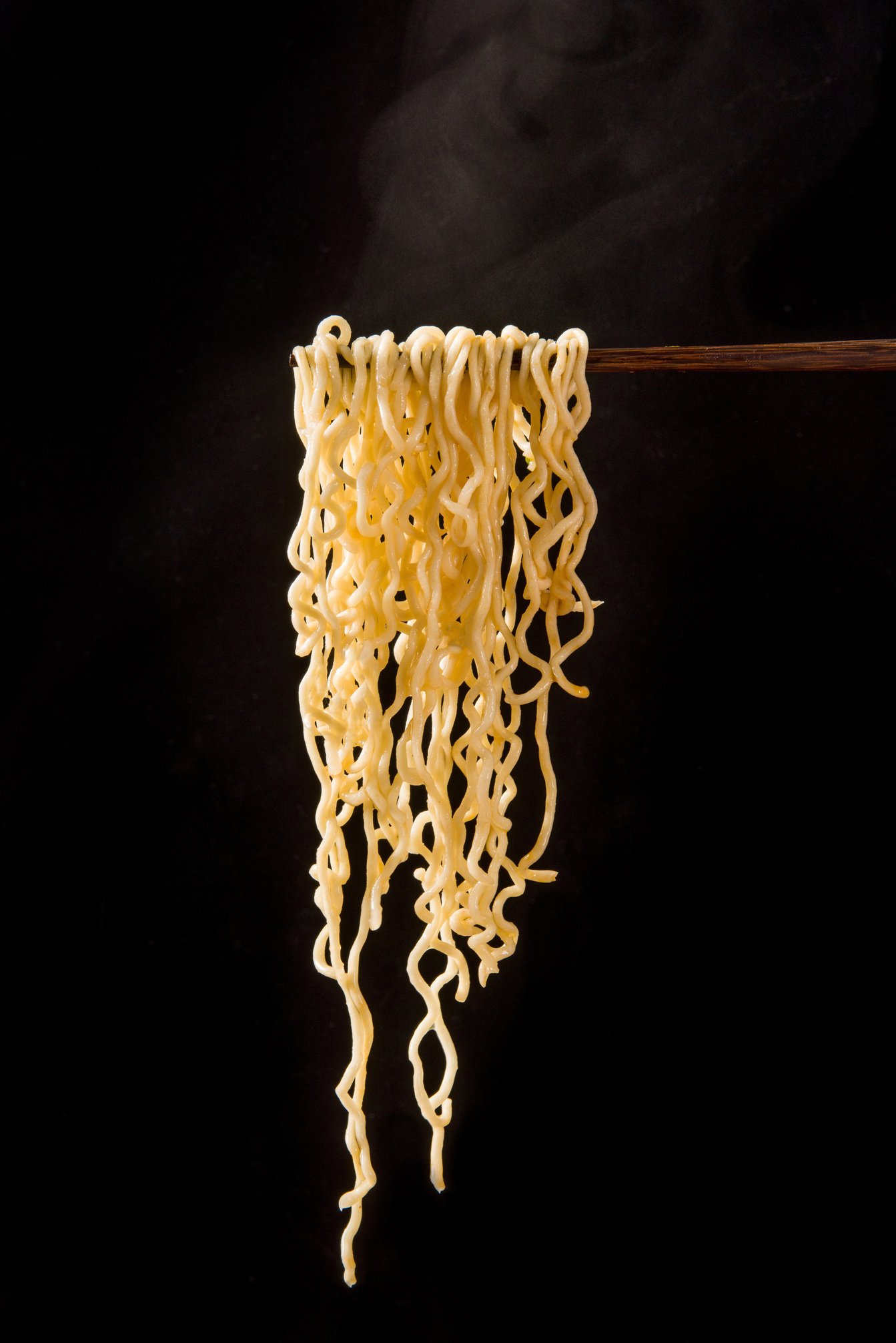 chopsticks with cooked instant noodles on black background